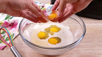 Cracking eggs into a glass mixing bowl