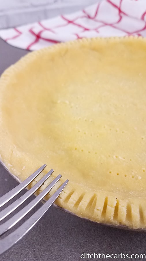 Easy no roll low-carb coconut flour pie crust being crimped with a fork