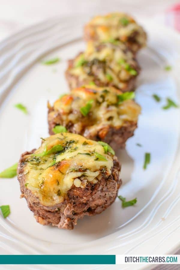 Mini meatloaf cupcakes with melted cheese and garnished with herbs