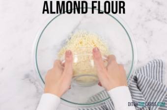 Hands placing almond flour into a mixing bowl