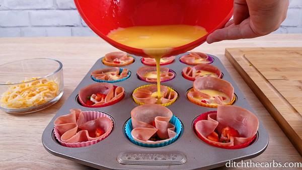 Pouring egg mixture into ham lined muffin trays