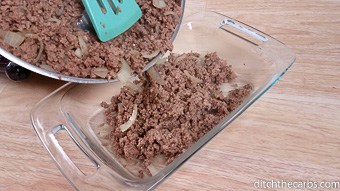 Cooked ground beef being placed into a baking dish