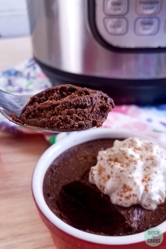 A spoon lifting chocolate instant pot mousse from the serving dish and whipped cream