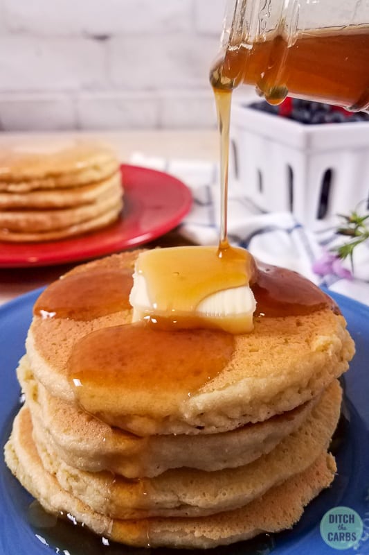 Almond flour pancakes stacked and being poured with maple syrup