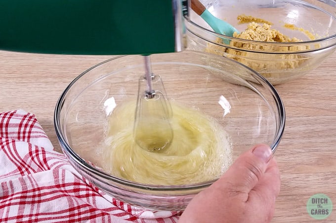 A mixing bowl with electric whisk whisking egg whites