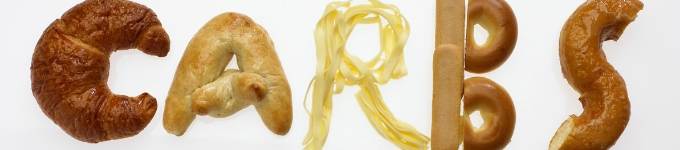 Pasta and bread styled into letters to spell \"carbs\"