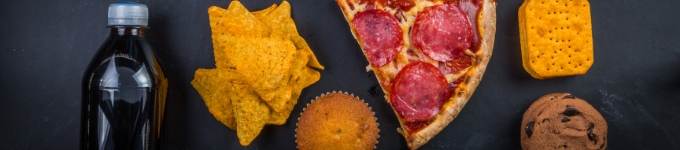 A selection of junk food, pizza and nacho chips on a black background