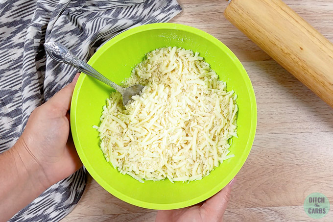 Adding shredded cheese to the mixing bowl