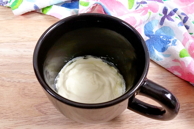Cream cheese and butter melted together in a small black mug.