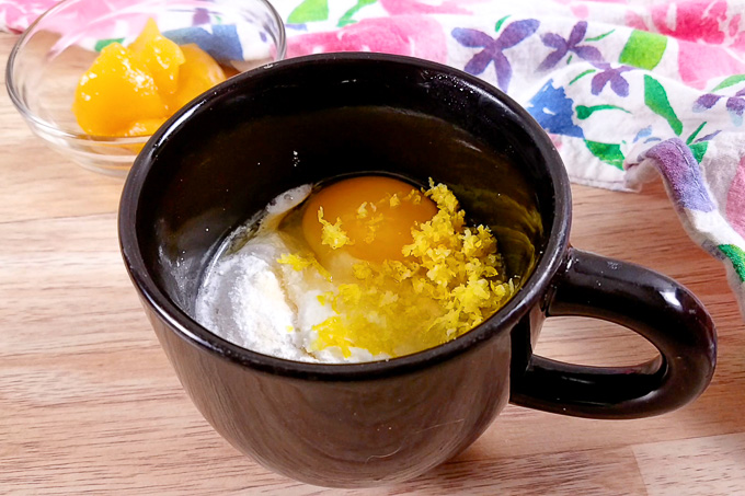 The ingredients for lemon curd low-carb mug cake are in a black mug. The ingredients have not been mixed yet.