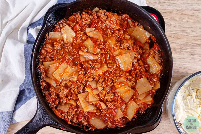 Noodles have been mixed into the meat sauce for low-carb skillet lasagna in a cast iron skillet.
