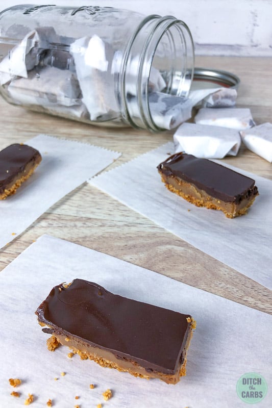Individual pieces of keto caramel slice resting on small parchments squares ready to be individually wrapped.