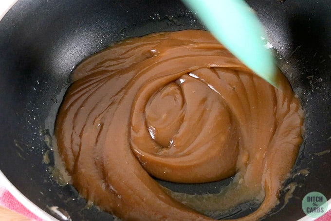 Stirring the caramel in a skillet for keto caramel slice.