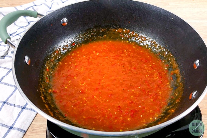 Spicy garlic sauce thickened in a black skillet.