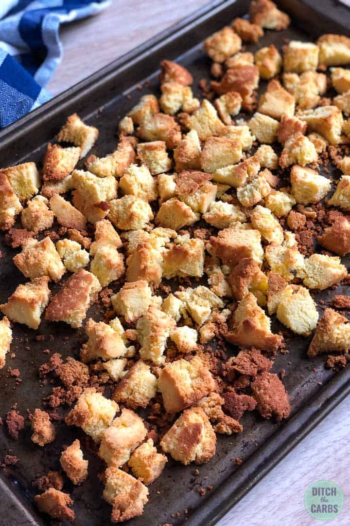 Keto cornbread broken into pieces and dried in the oven on a large baking sheet.