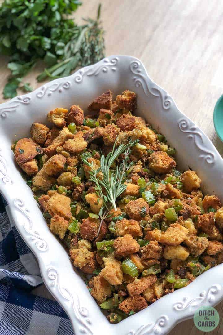 Low-carb and keto stuffing in a white serving dish with fresh herbs on top as garnish.