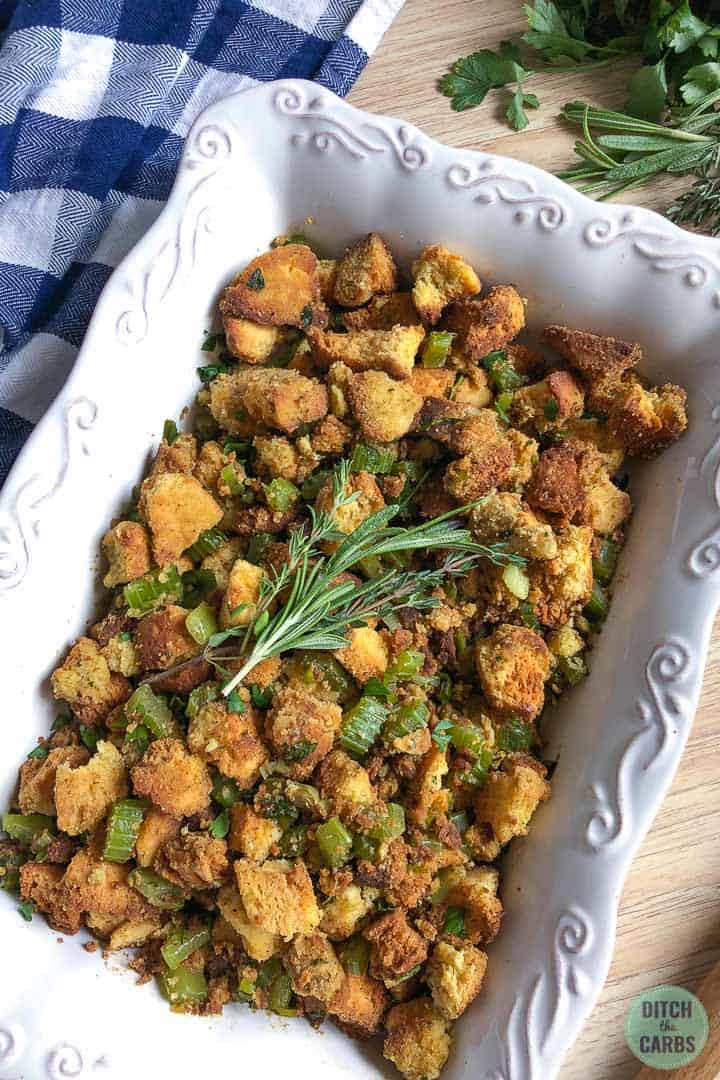Keto and Low-Carb stuffing in a white serving dish with sprig of fresh herbs on top as garnish.