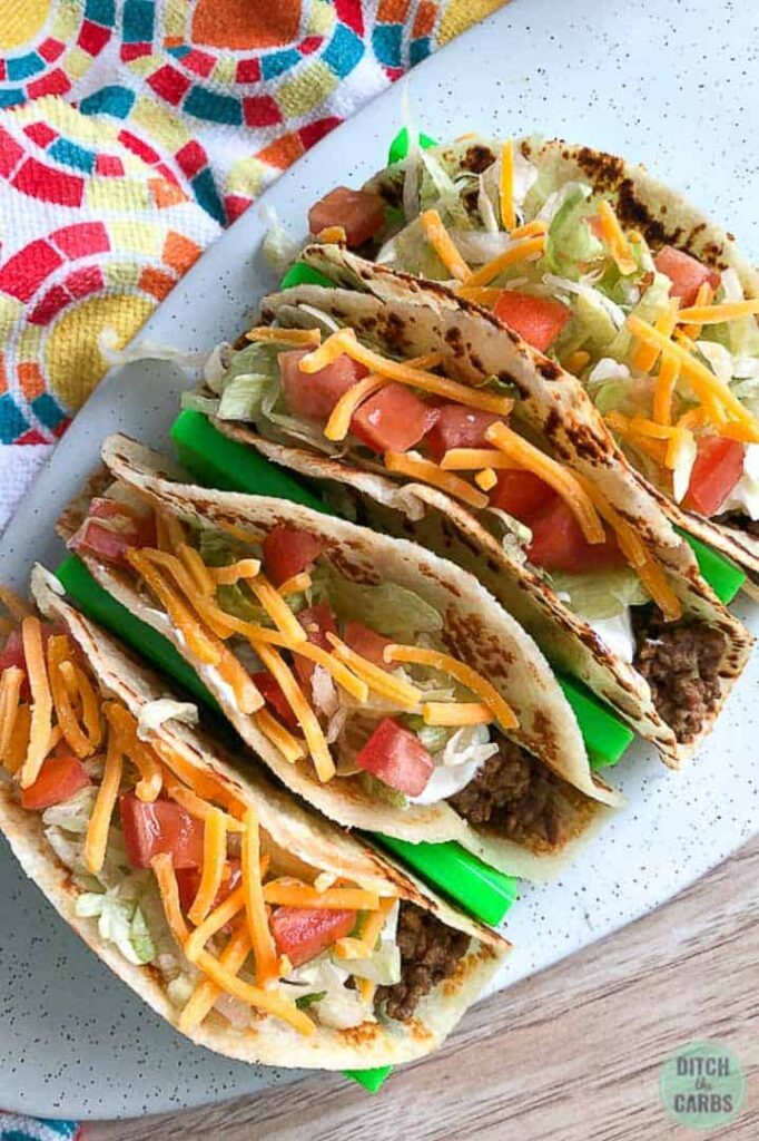 Four copycat keto Taco Bell soft tacos on a neon green taco holder. Picture is from above.