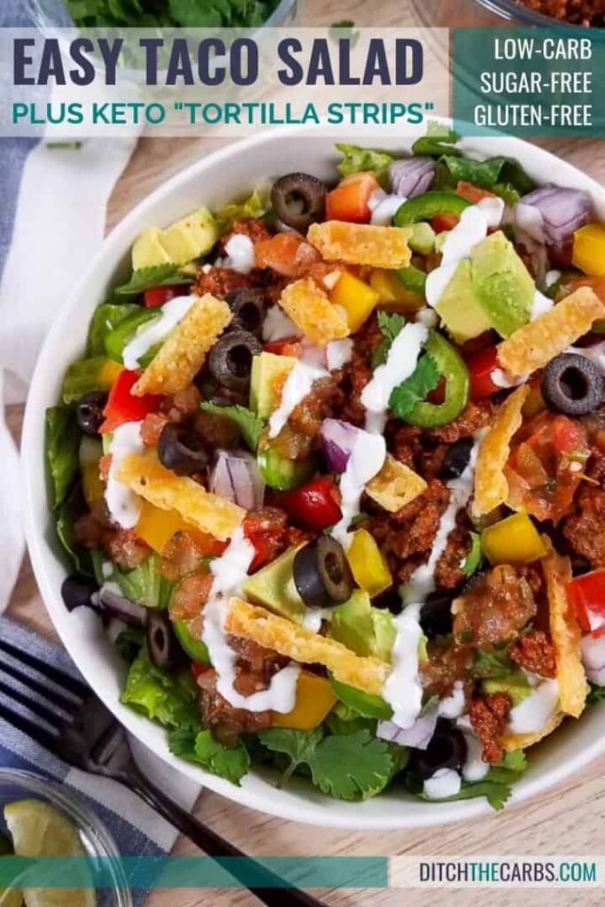 taco salad served in a white bowl drizzled with creamy sauces