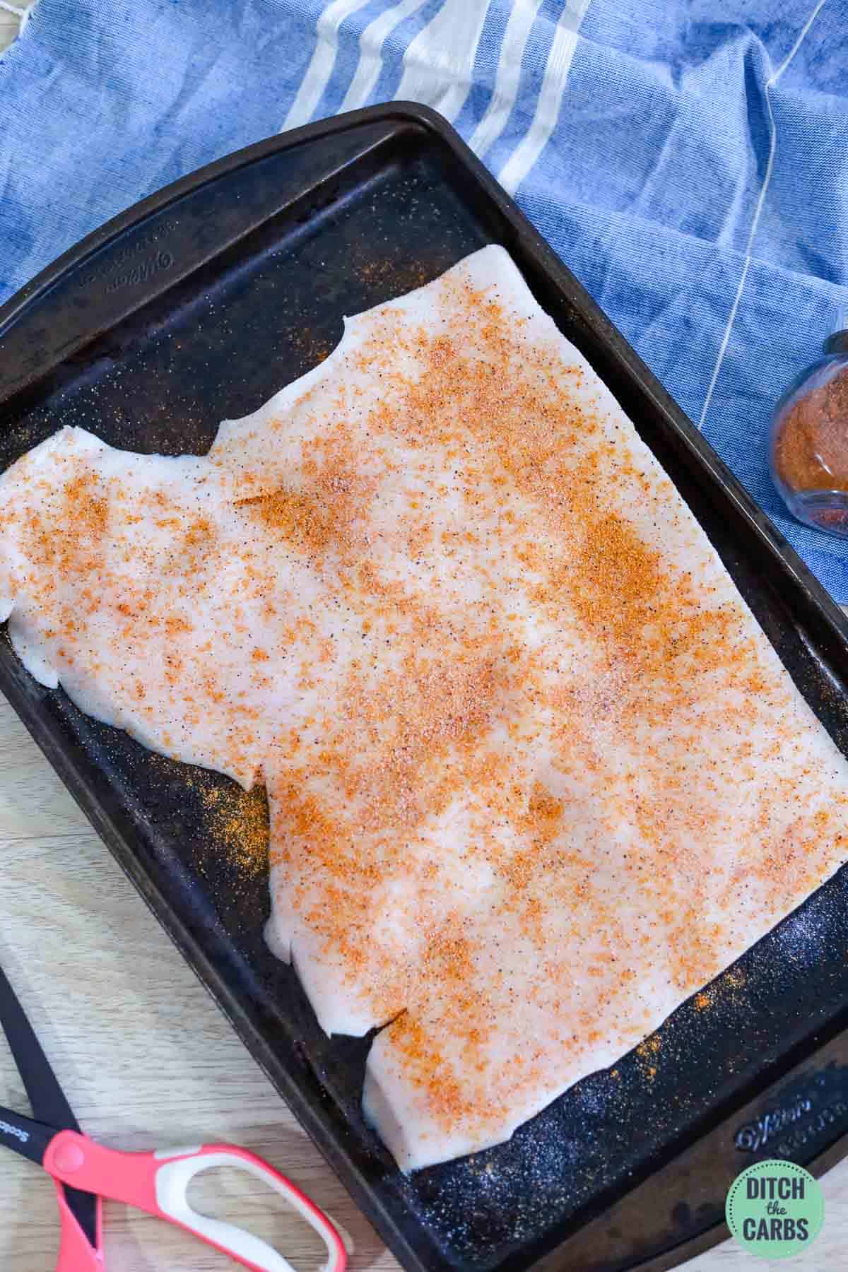 pork skin seasoned on a sheet pan to make pork rinds