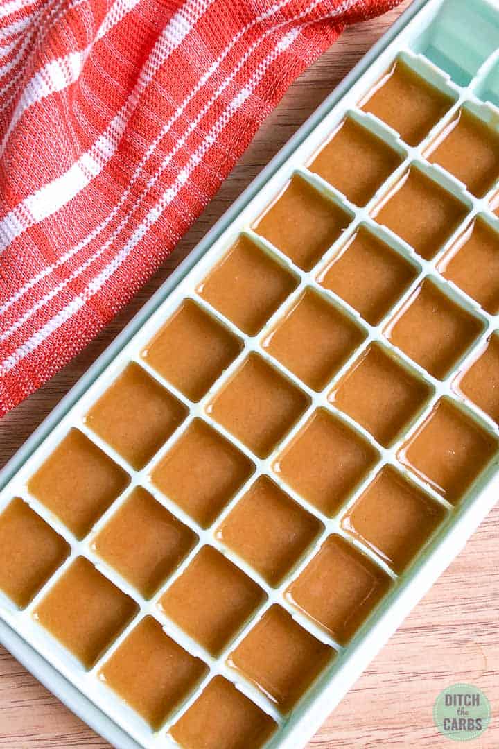 Light green silicone ice cube tray with 32 squares filled with peanut butter fudge. The fudge is still warm and hasn't hardened yet. 