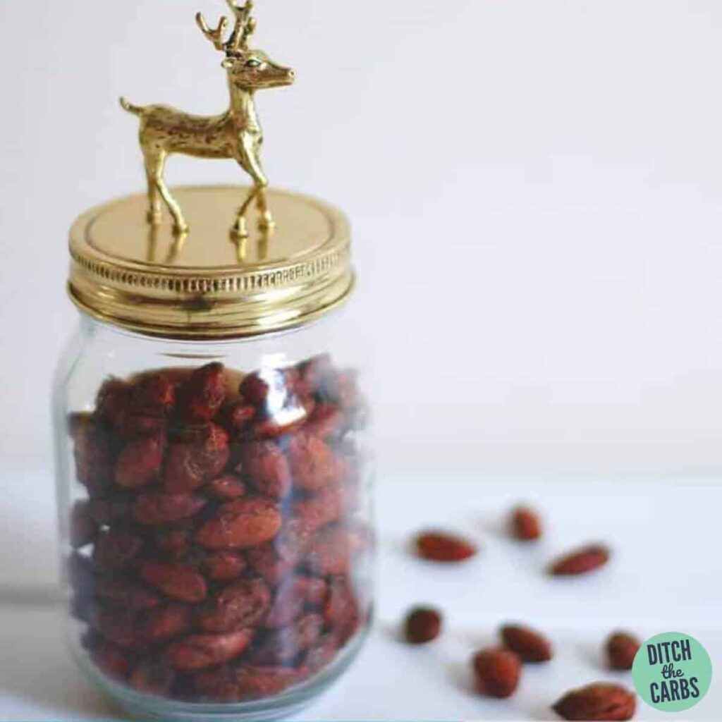 Roasted almonds in a glass jar with a Christmas decoration on the gold lid