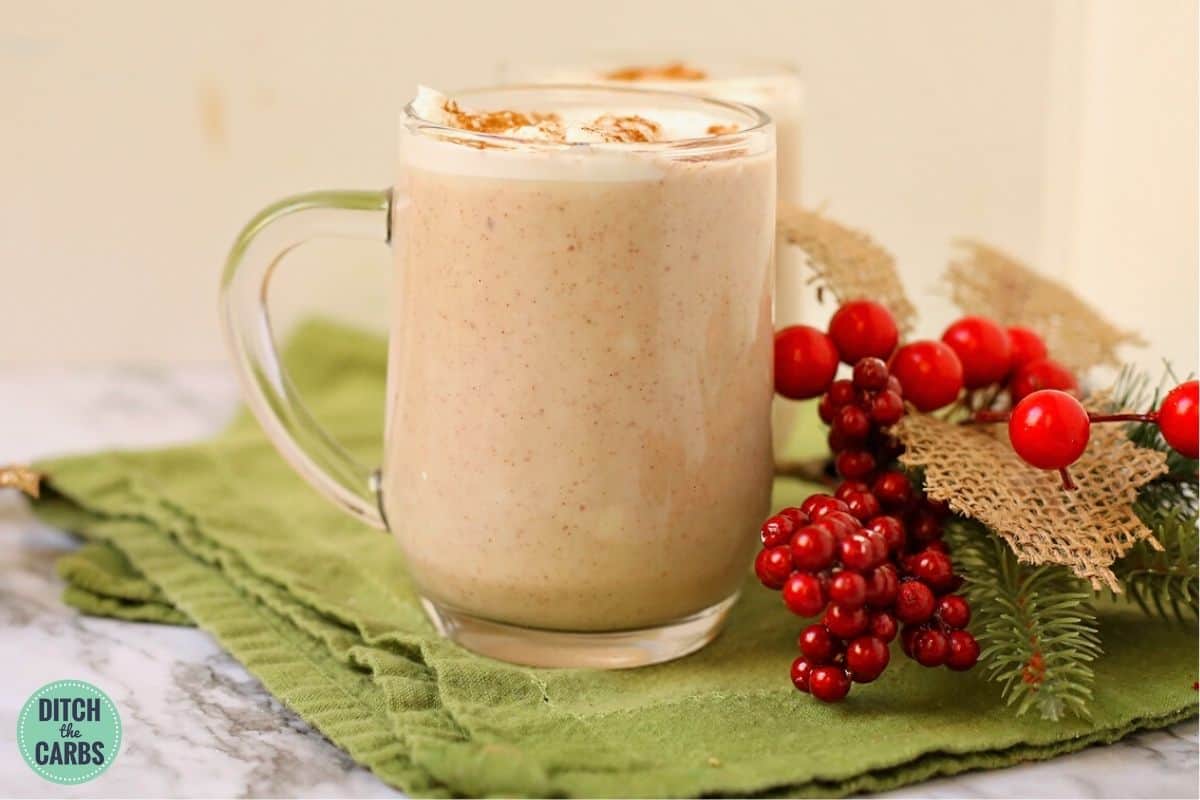 creamy keto eggnog served in two glass coffee mugs with Christmas decorations