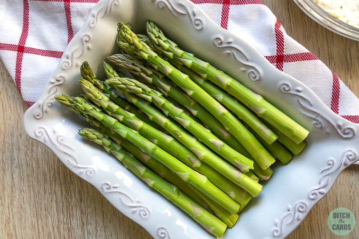 Asparagus with the woody ends removed in a white baking pan.