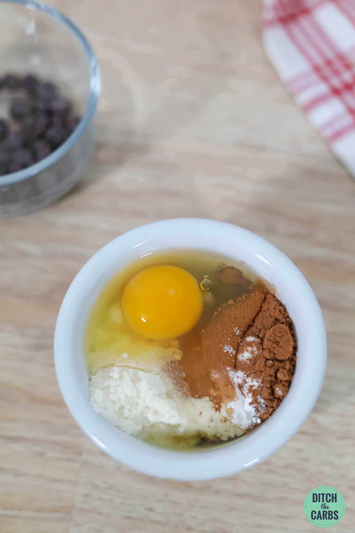 raw egg, sweetener, and cocoa in a white mug