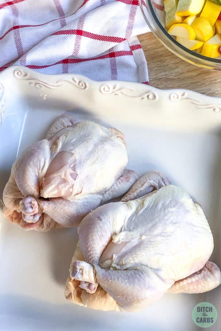 Two defrosted Cornish hens resting in a white baking pan ready to be seasoned.