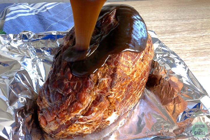 A close up of roast ham being covered with a sugar-free glaze before cooking