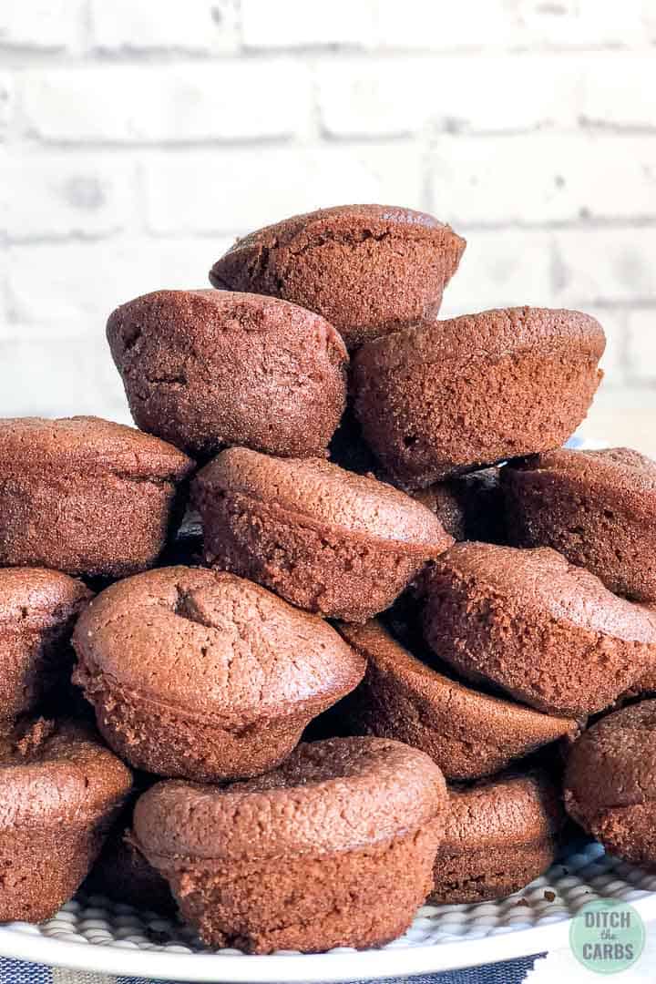 Keto dairy-free brownies baked as mini muffins. They are stacked in a pile on top of each other on a plate. 