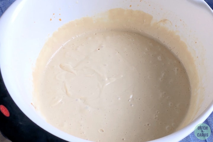 Peanut butter cheesecake filling mixed together in a white mixing bowl.