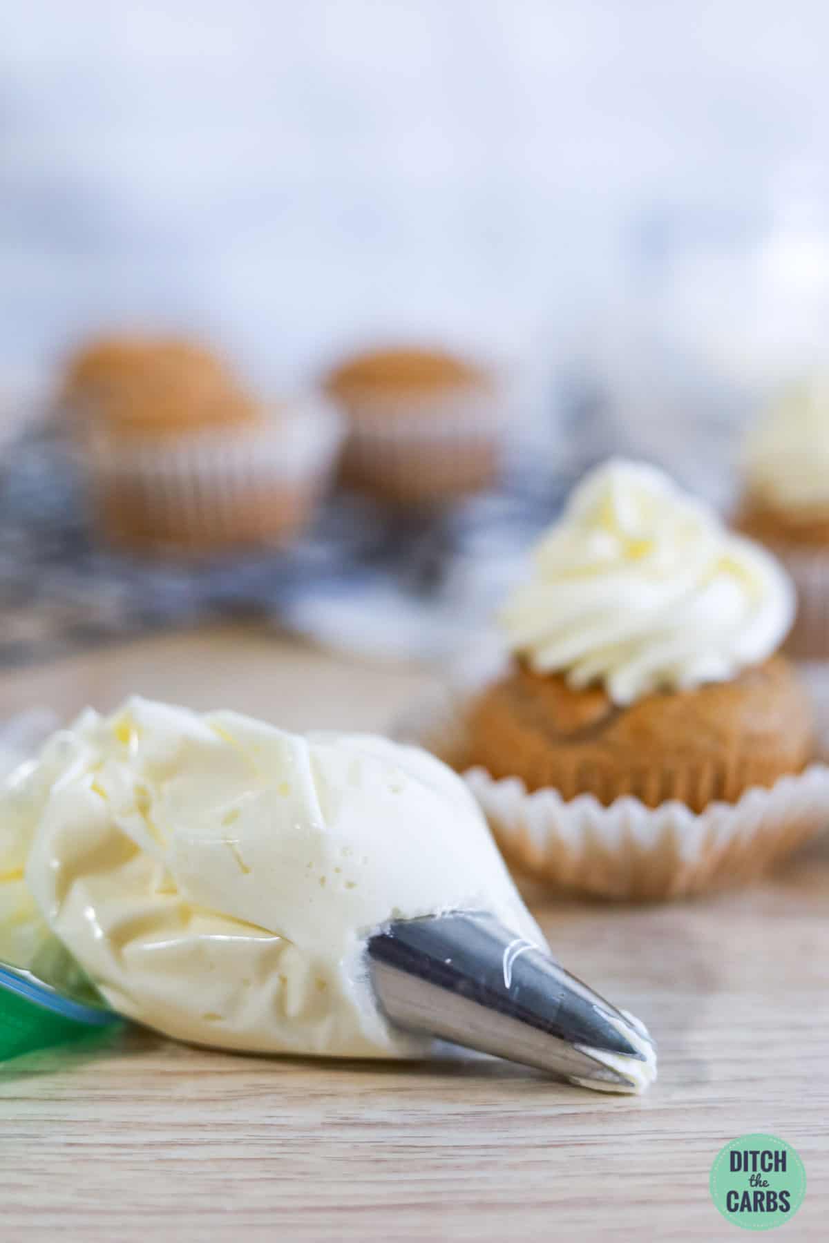 a piping bag with cream cheese frosting and some cupcakes