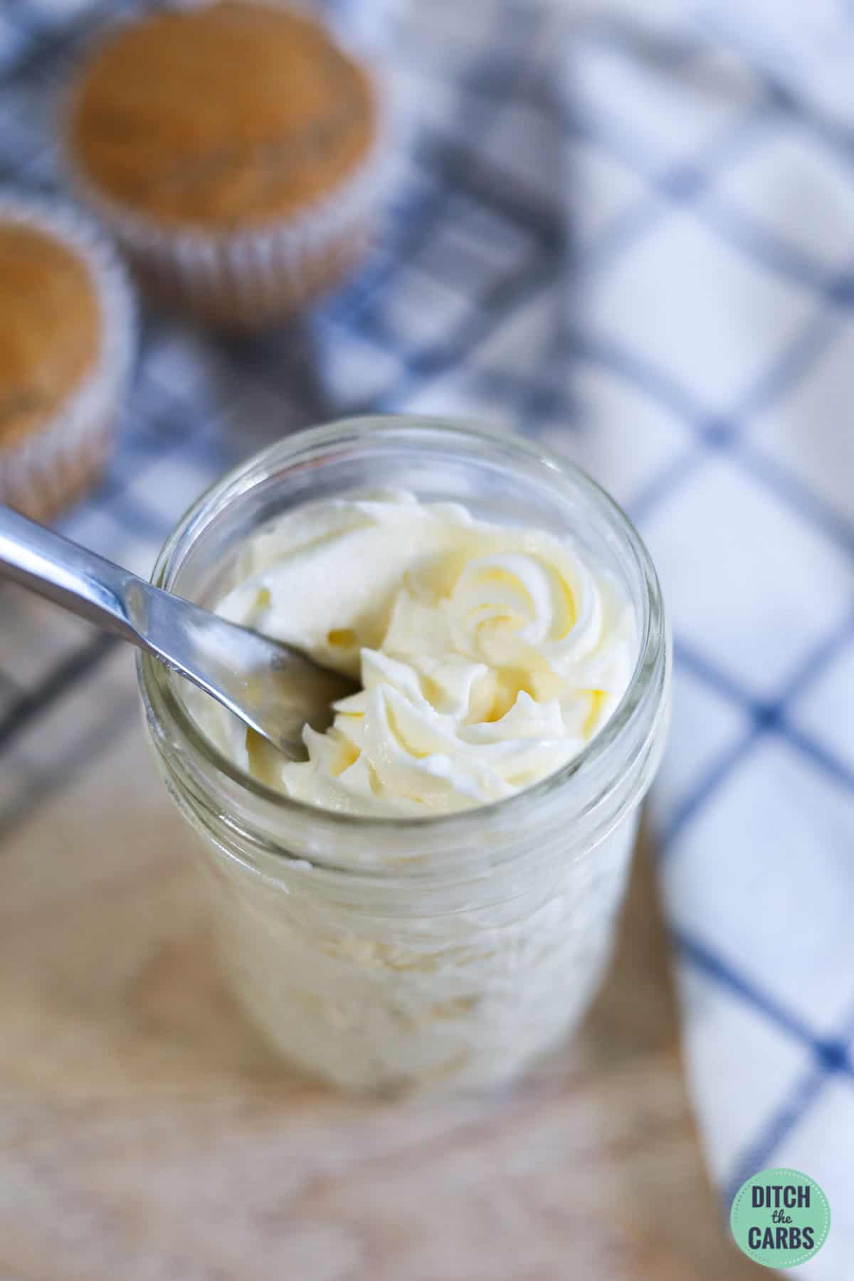 a glass jar with whipped frosting and a spoon