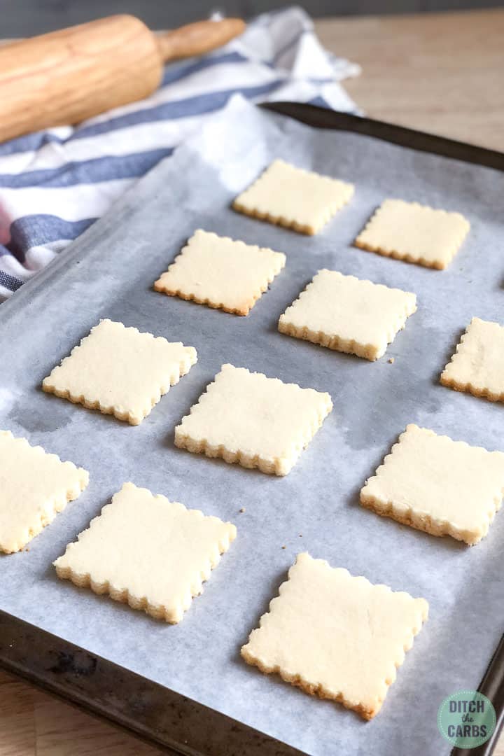 Freshly baked keto shortbread cookies cooling on the baking sheet lined with white parchment paper.