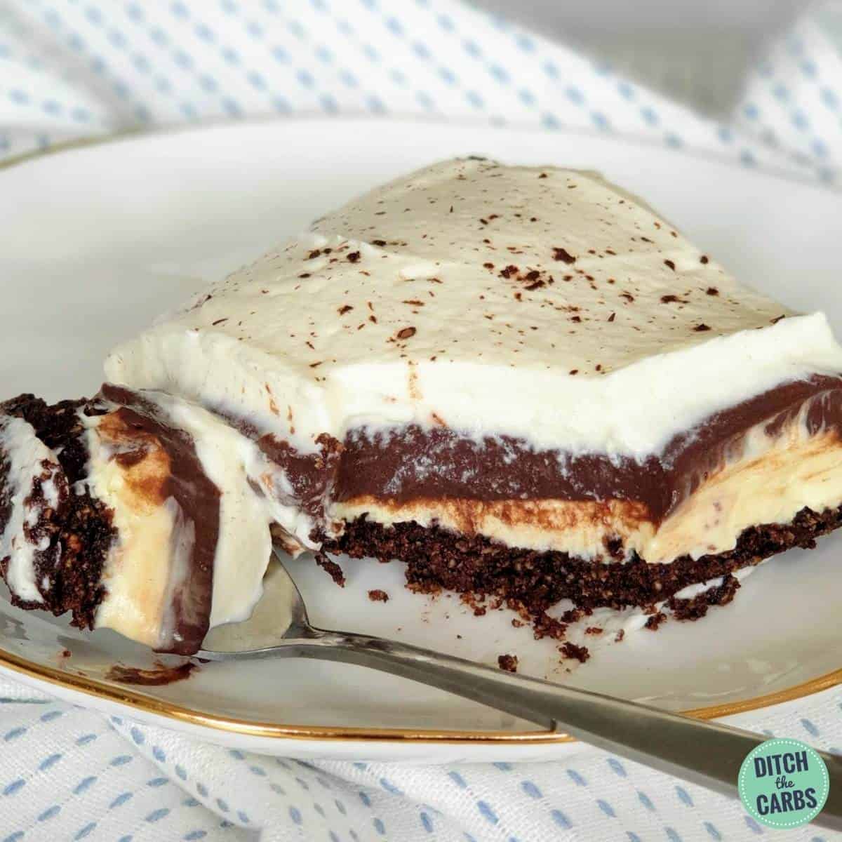 A slice of chocolate lasagna dessert sliced on a white plate and a fork with a bite taken