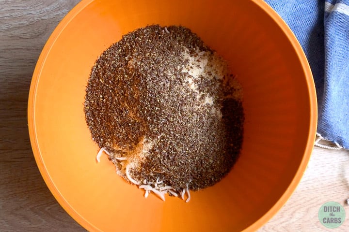 Shredded mozzarella, almond flour, and ground flaxseed in an orange bowl.