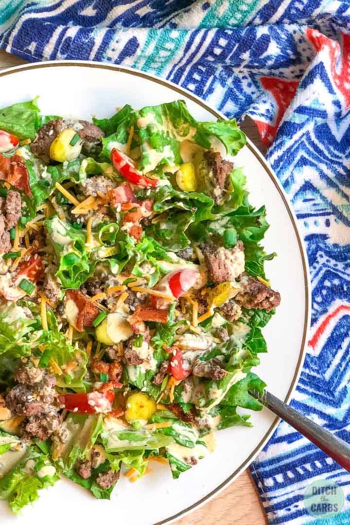 Overhead shot of keto hamburger salad showing half the plate. A blue patterned towel is in the back.