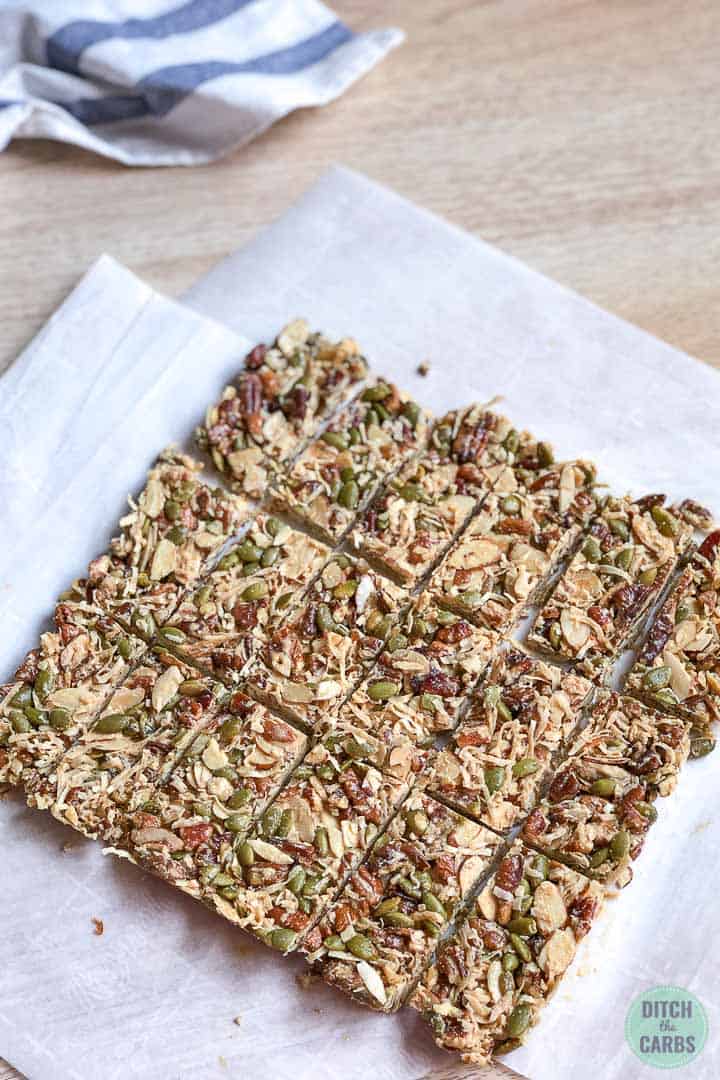 Frozen granola bars in a square cut into 18 bars. They are resting on a piece of white parchment paper.