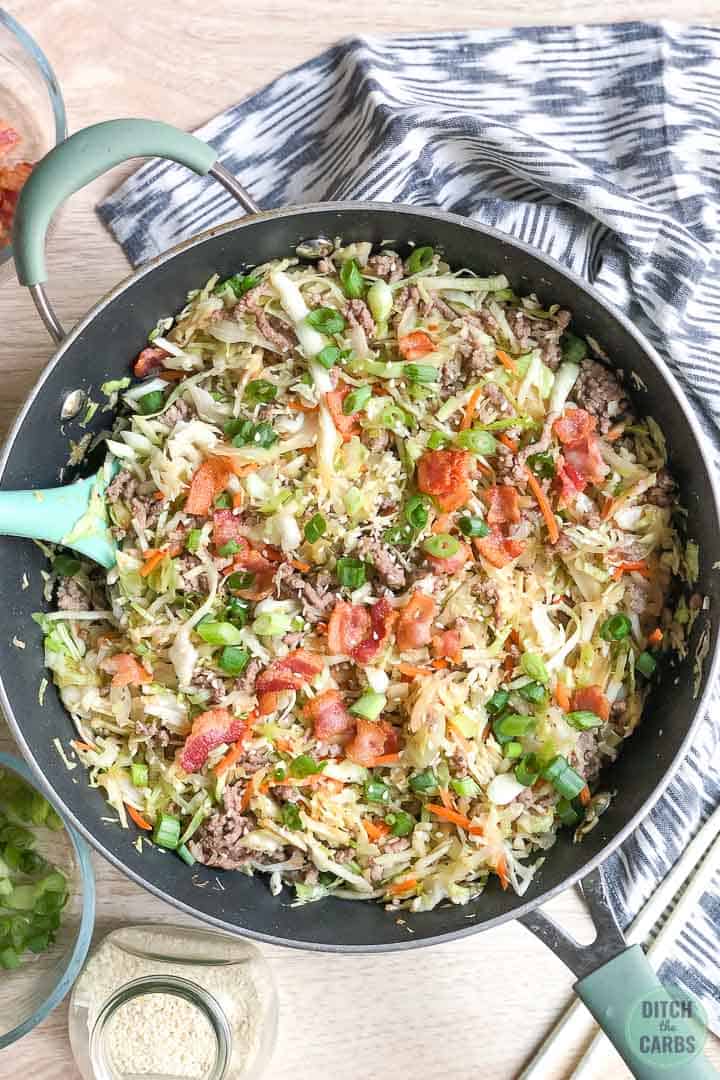 Cooked crack slaw in a skillet topped with bacon and green onions.