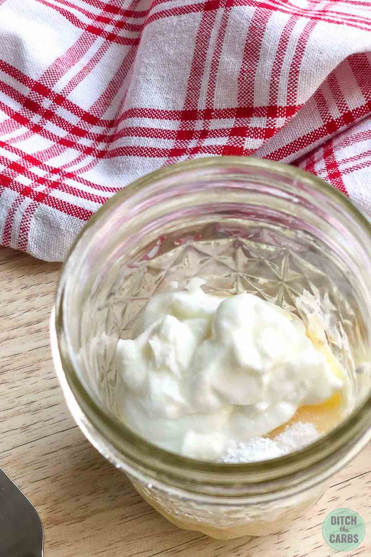All the keto mug cheesecake ingredients have been added to a clear glass jar. They are ready to be mixed together.