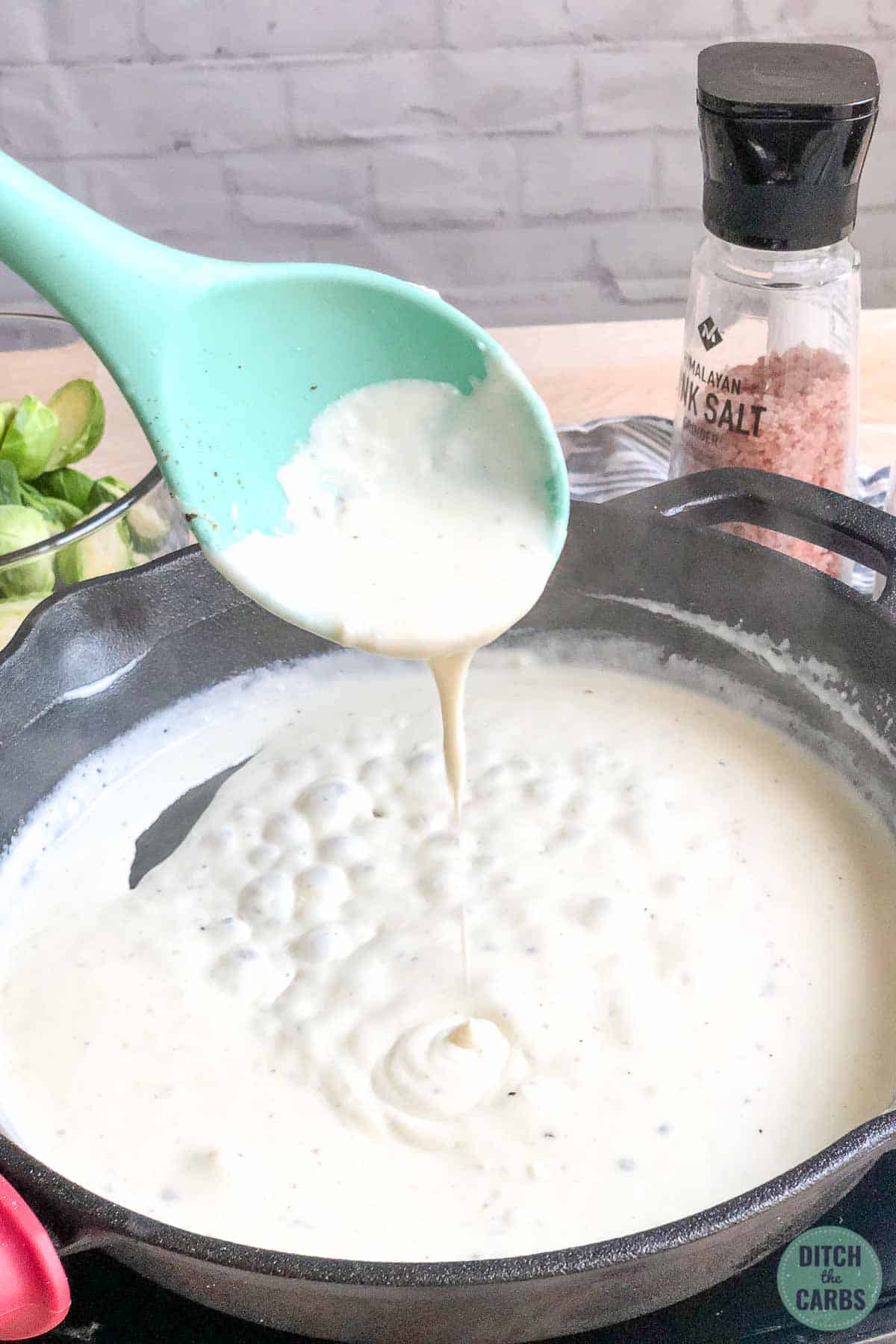 Making a heavy cream sauce with cheese and seasoning in a cast iron skillet.  