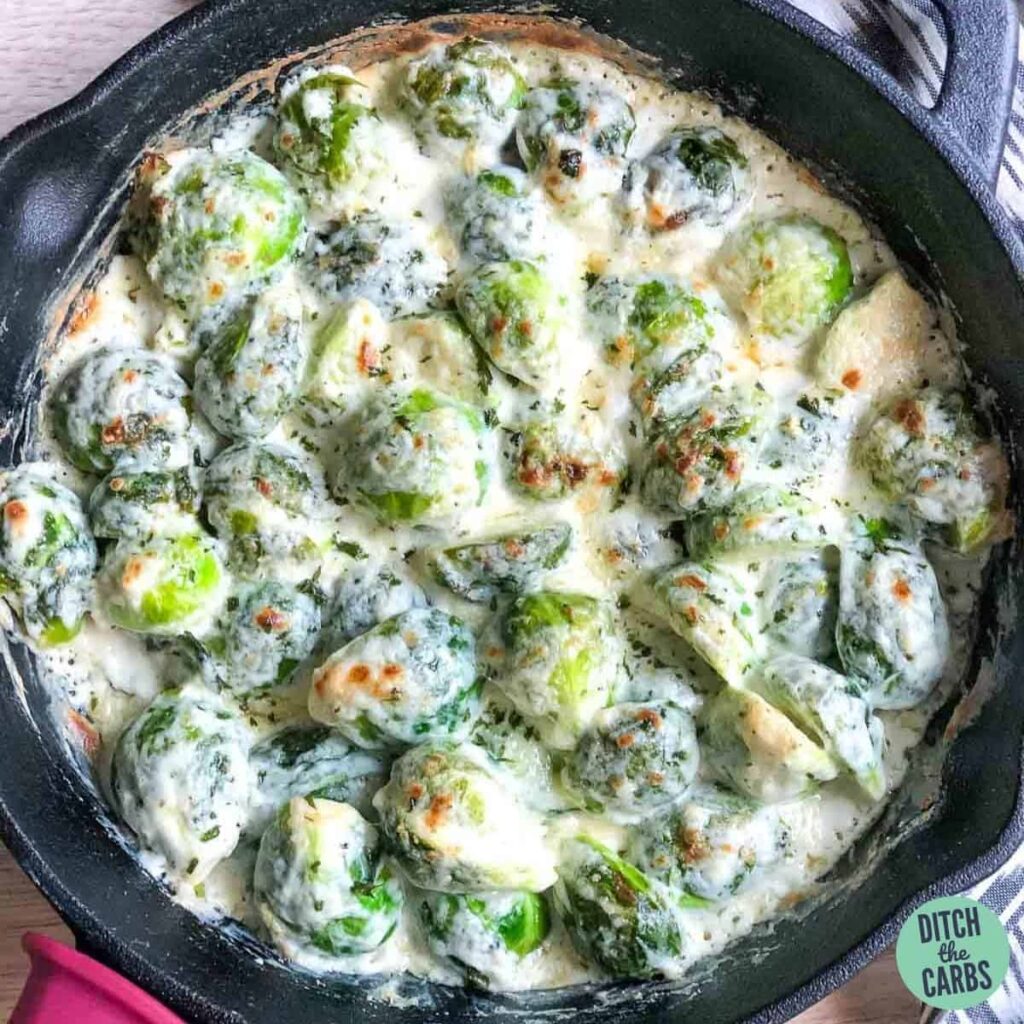 Tasty baked creamed brussels sprouts cooling on the counter in a cast-iron skillet.