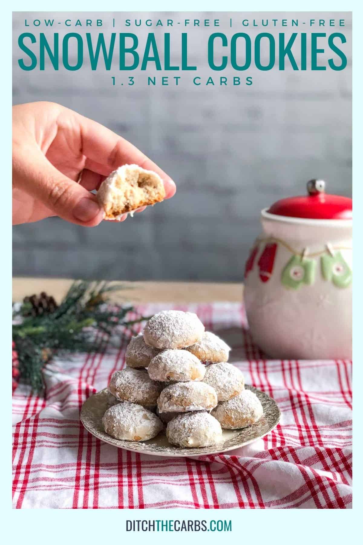 hand holding a keto snowball cookie with a plate of snowball cookies underneath