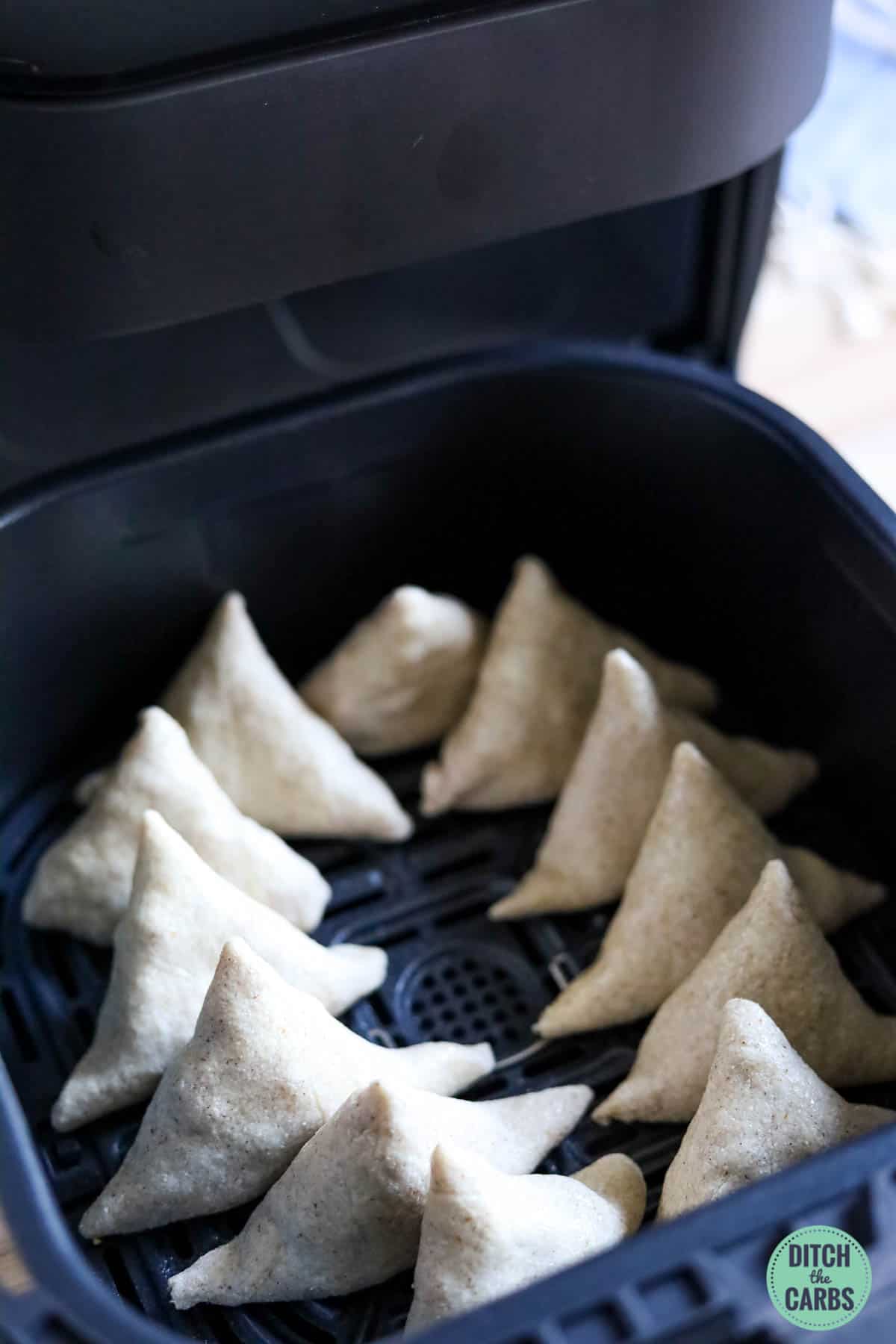 keto samosas cooking in an air fryer basket