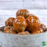 Keto sweet and sour meatballs piled high in a bowl with sesame seed sprinkled on top.
