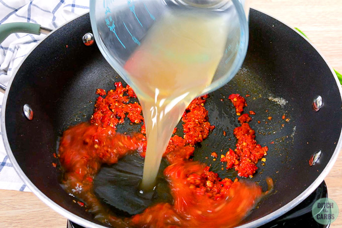 Broth being poured into spicy garlic sauce.