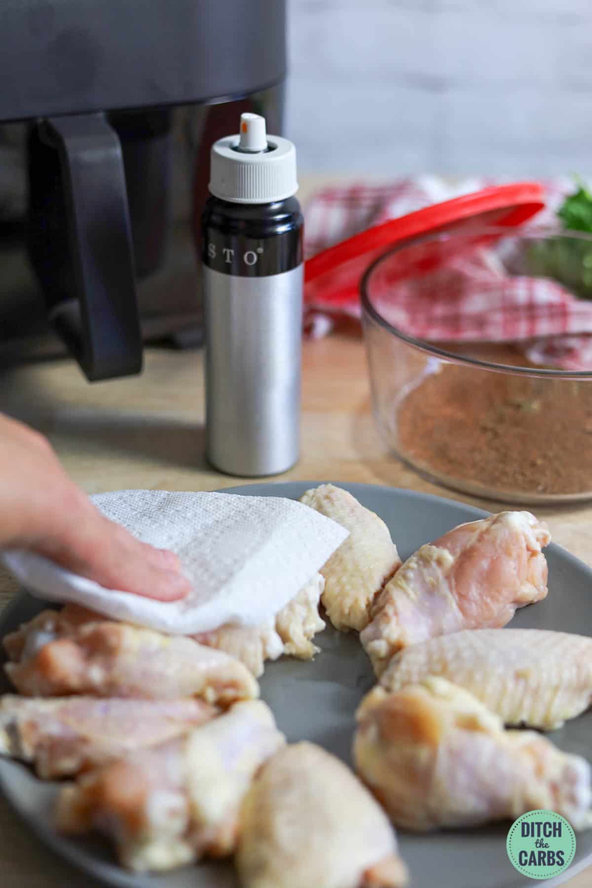 Demonstrates how to get crispy wings in the air fryer by patting chicken dry.