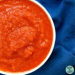 A bowl of homemade ketchup sitting on a blue cloth